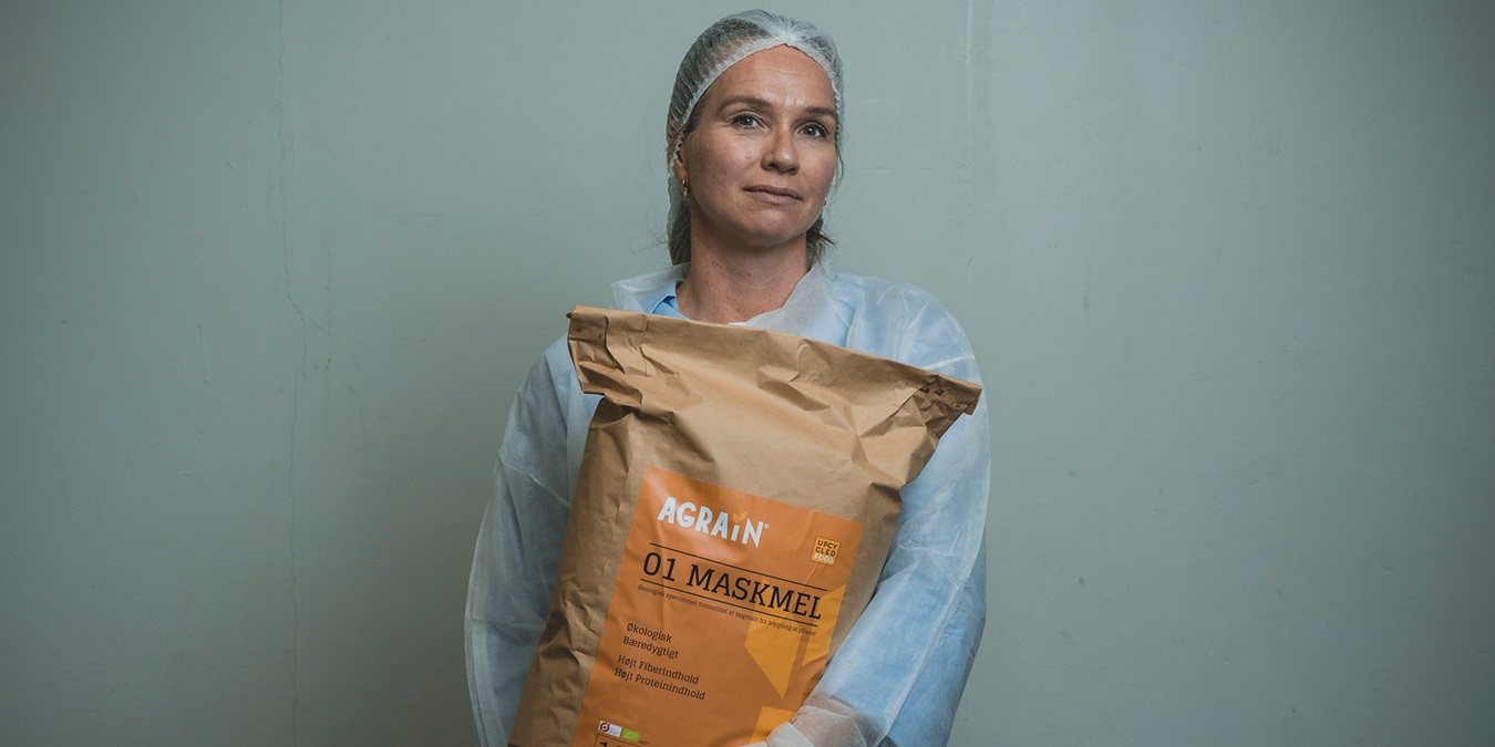 Aviaja Andersen står med en sæk maskmel iført hår net