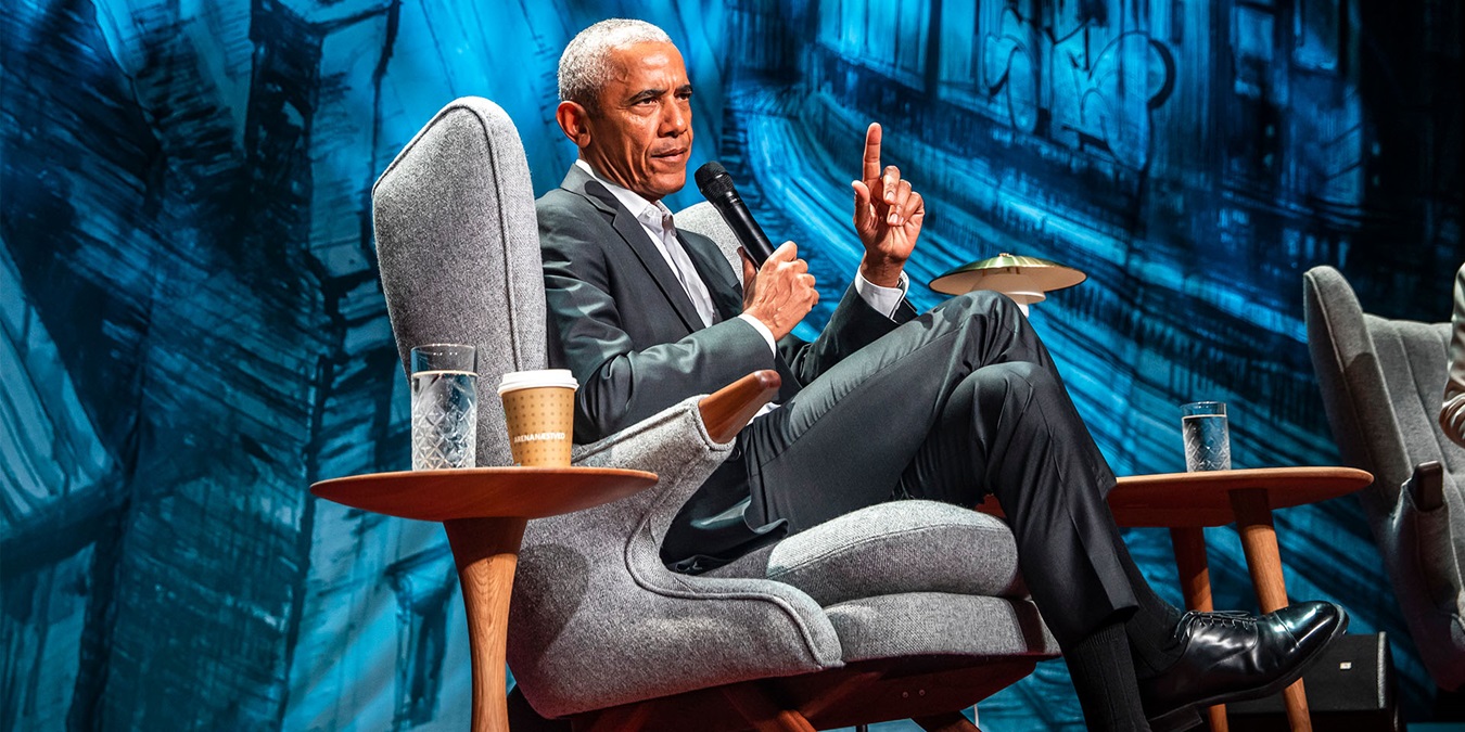 Barack Obama sidder i en grå, dansk design lænestol med en løftet pegefinger