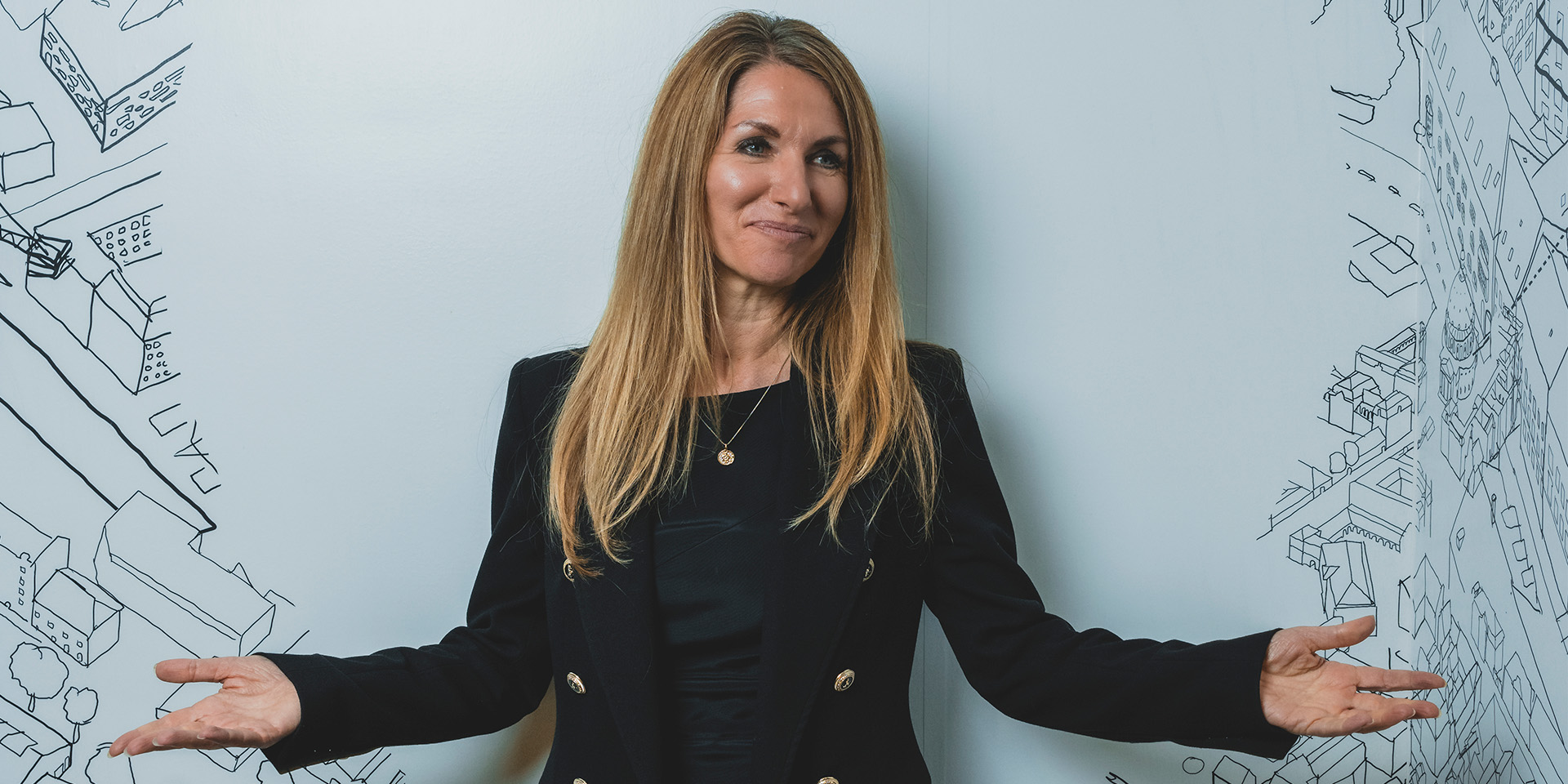 Bianca Bruhn står med spredte arme foran hvid væg