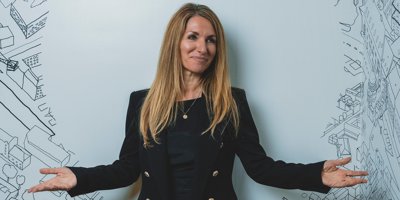 Bianca Bruhn står med spredte arme foran hvid væg