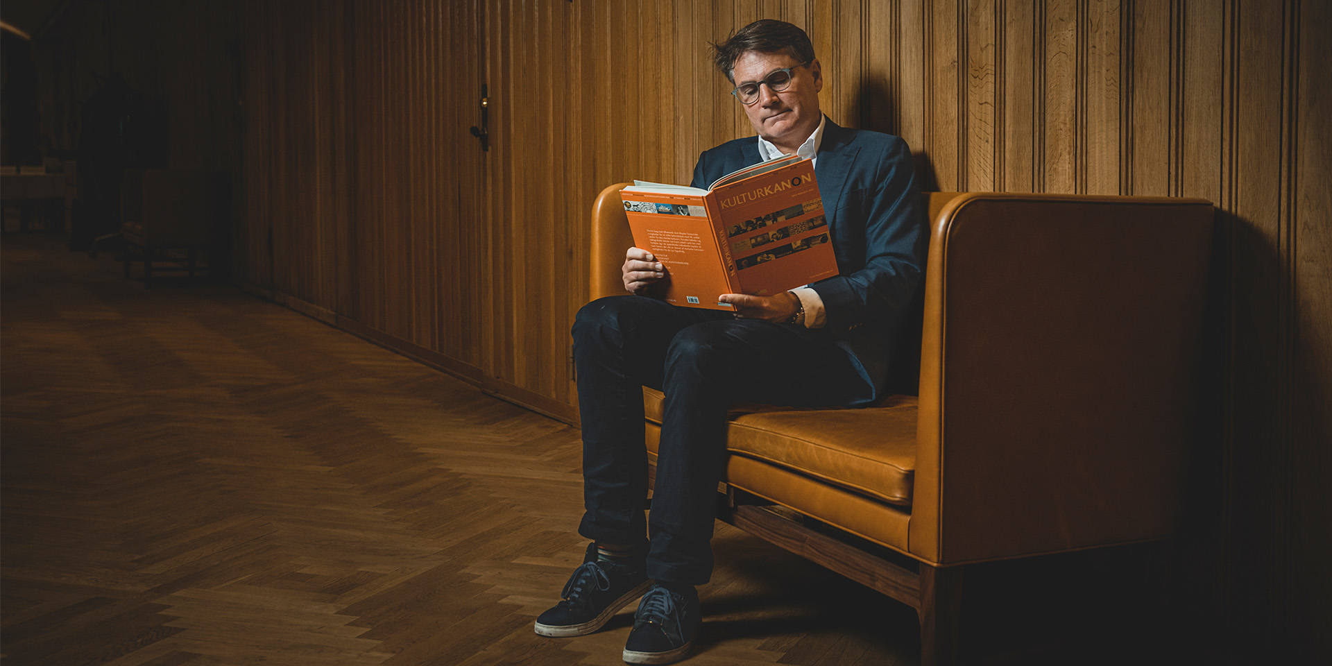 Brian Mikkelsen sidder i en sofa og læser i kulturkanon