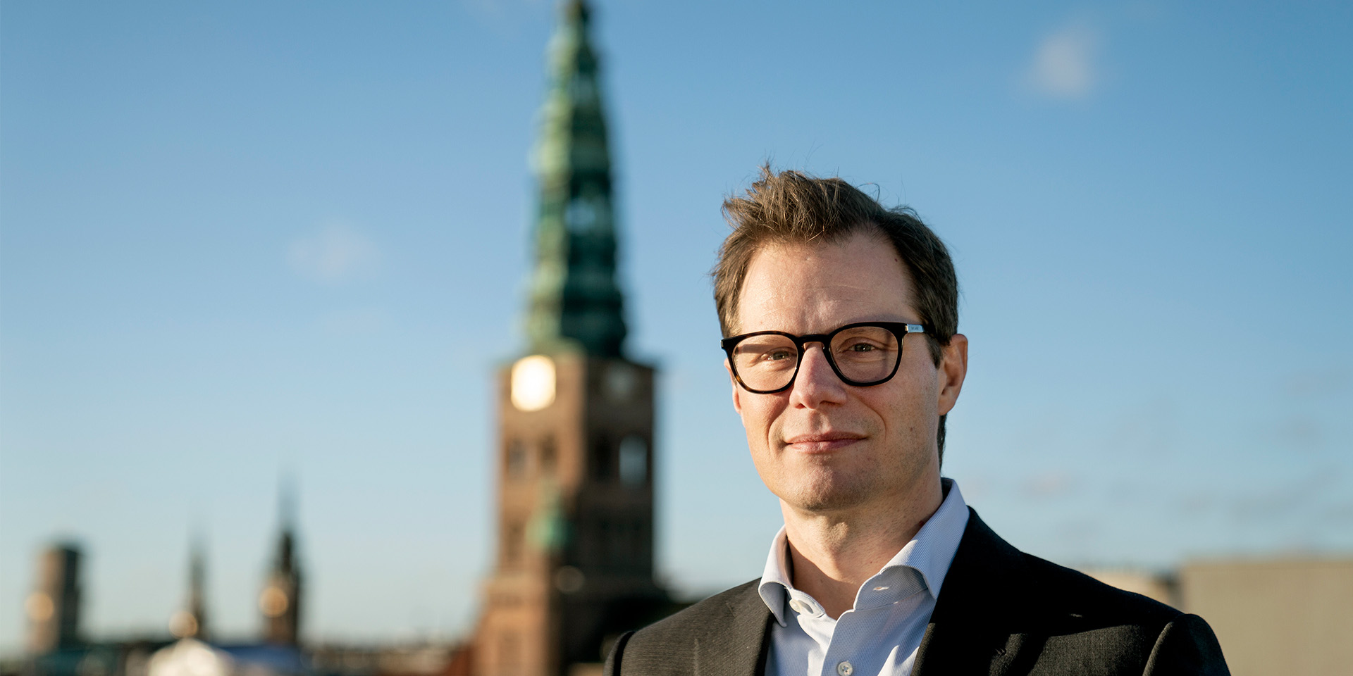 Carsten Egeriis står med flot bygning i baggrunden