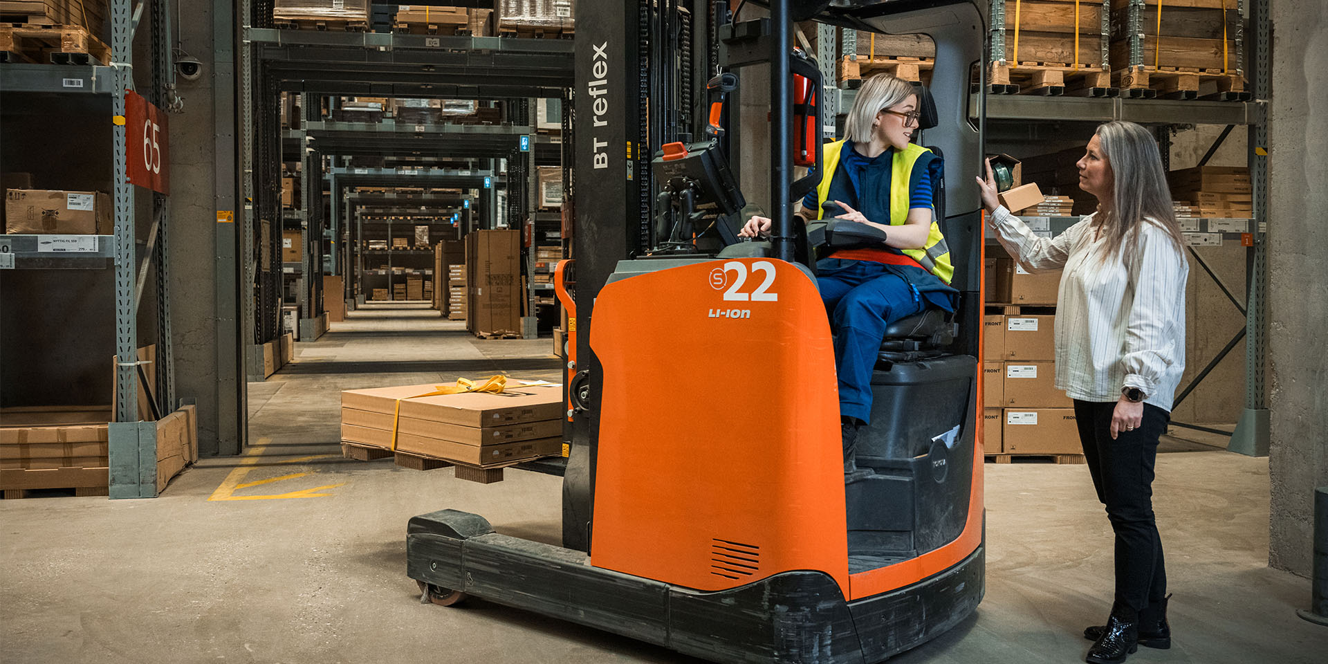Charlotte Jensen står og snakker med en kvindelig gaffeltruckfører i IKEAs varelager