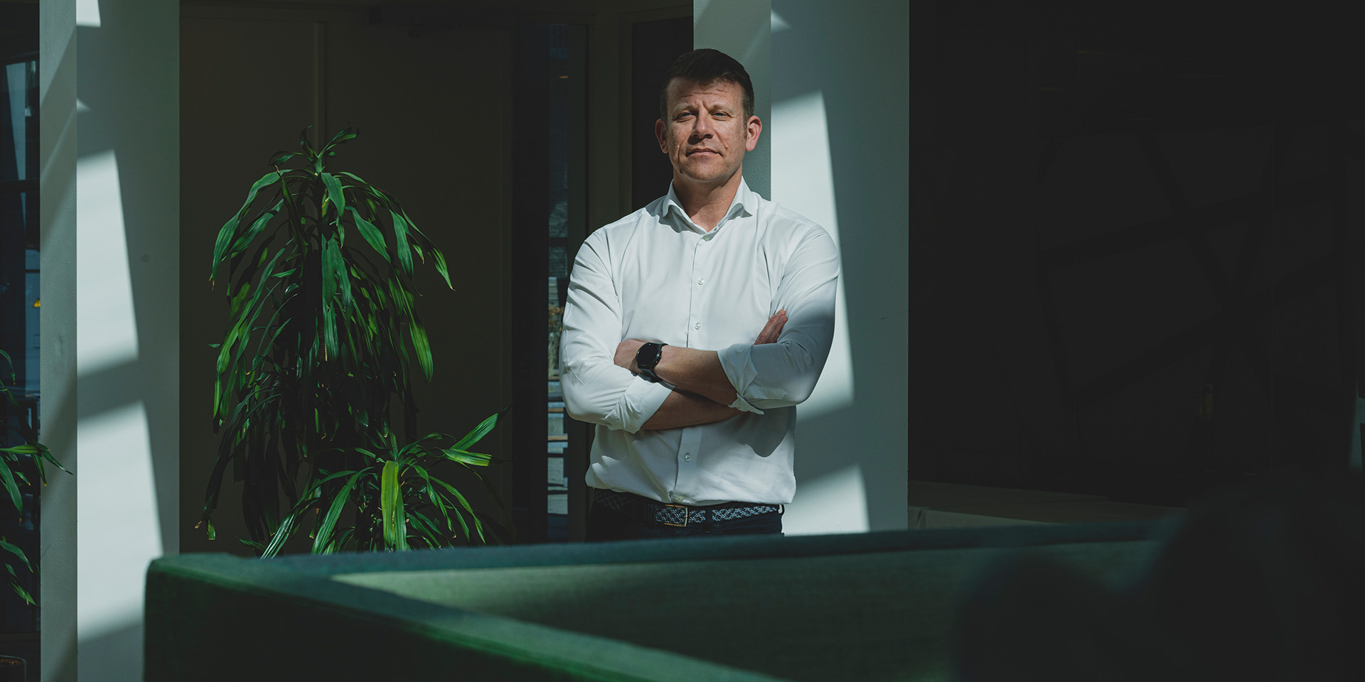 Christian Lauritzen står ved en sofa og en plante