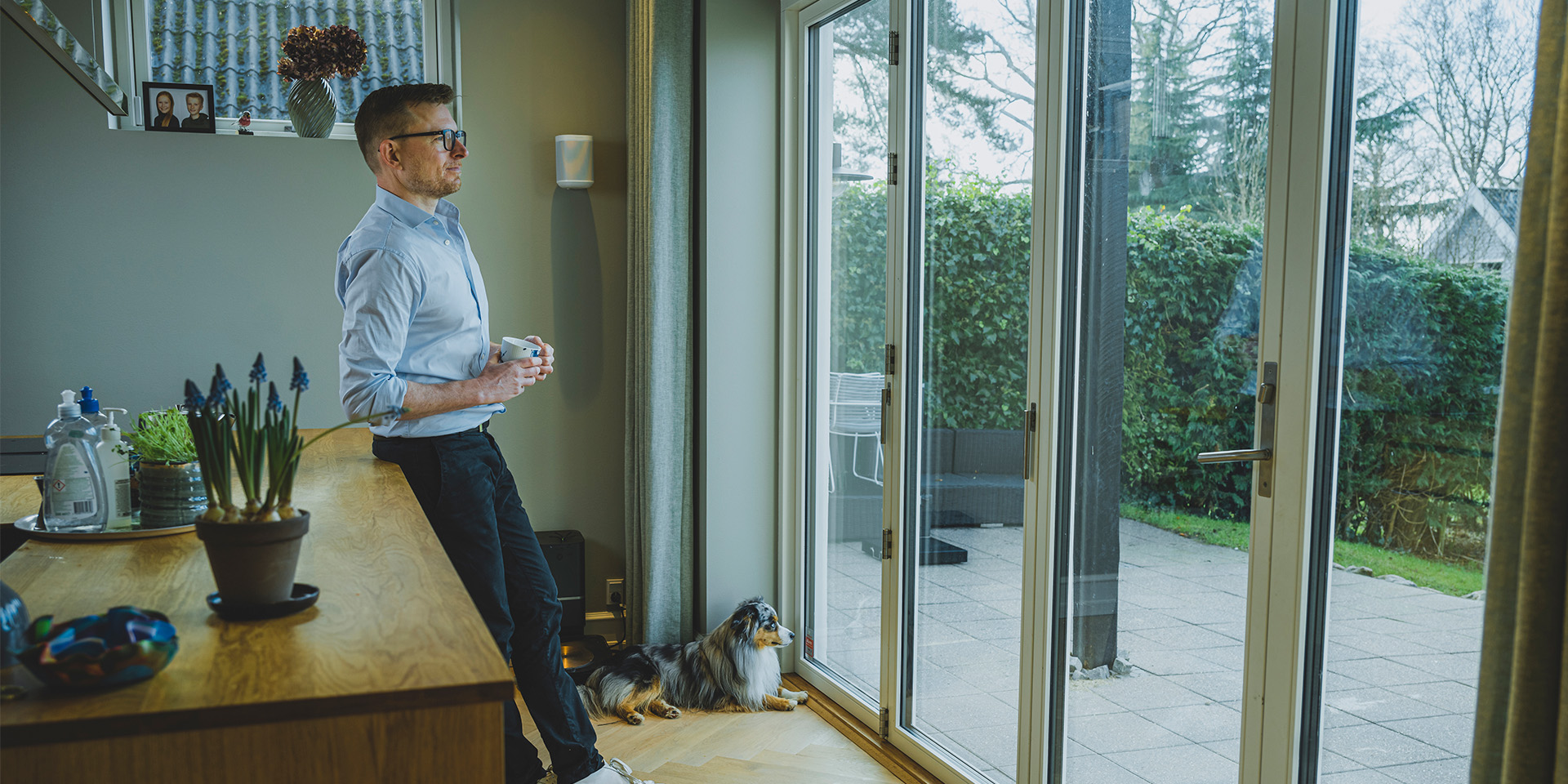 Eske Gunge står i sit køkken og ser ud i sin have