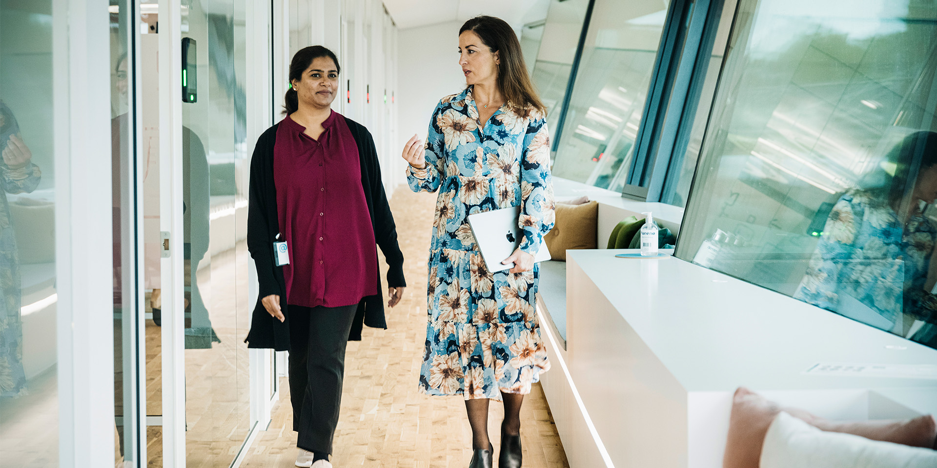 Figen Cayan går og snakker med en medarbejder på kontorgangen