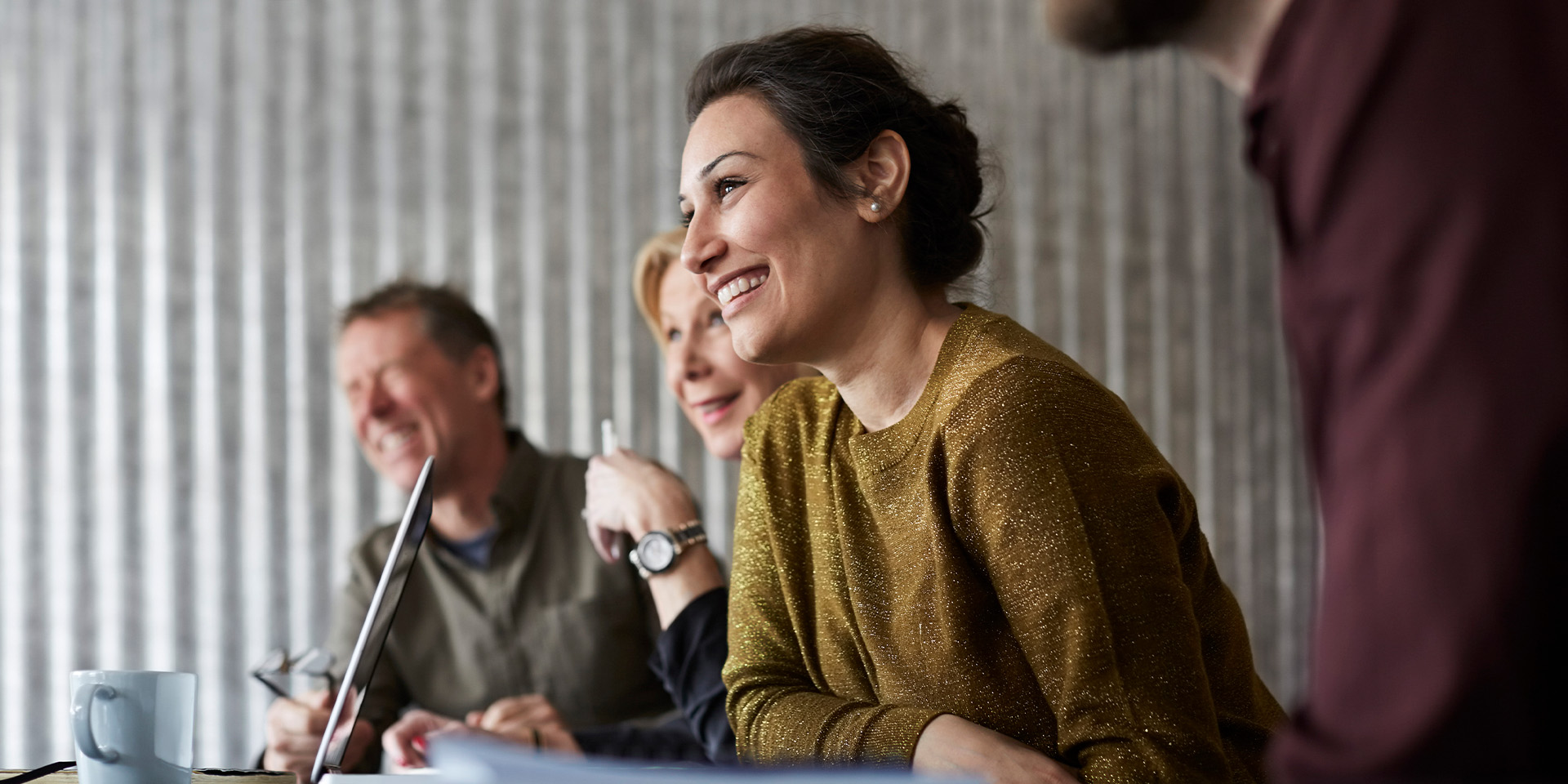 En masse mennesker sidder og smiler til et møde