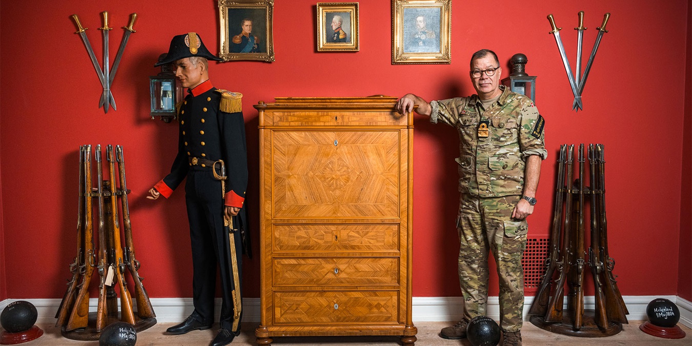 Henrik Rybjerg læner sig op ad en kommode i blandt søfartens historiske genstande