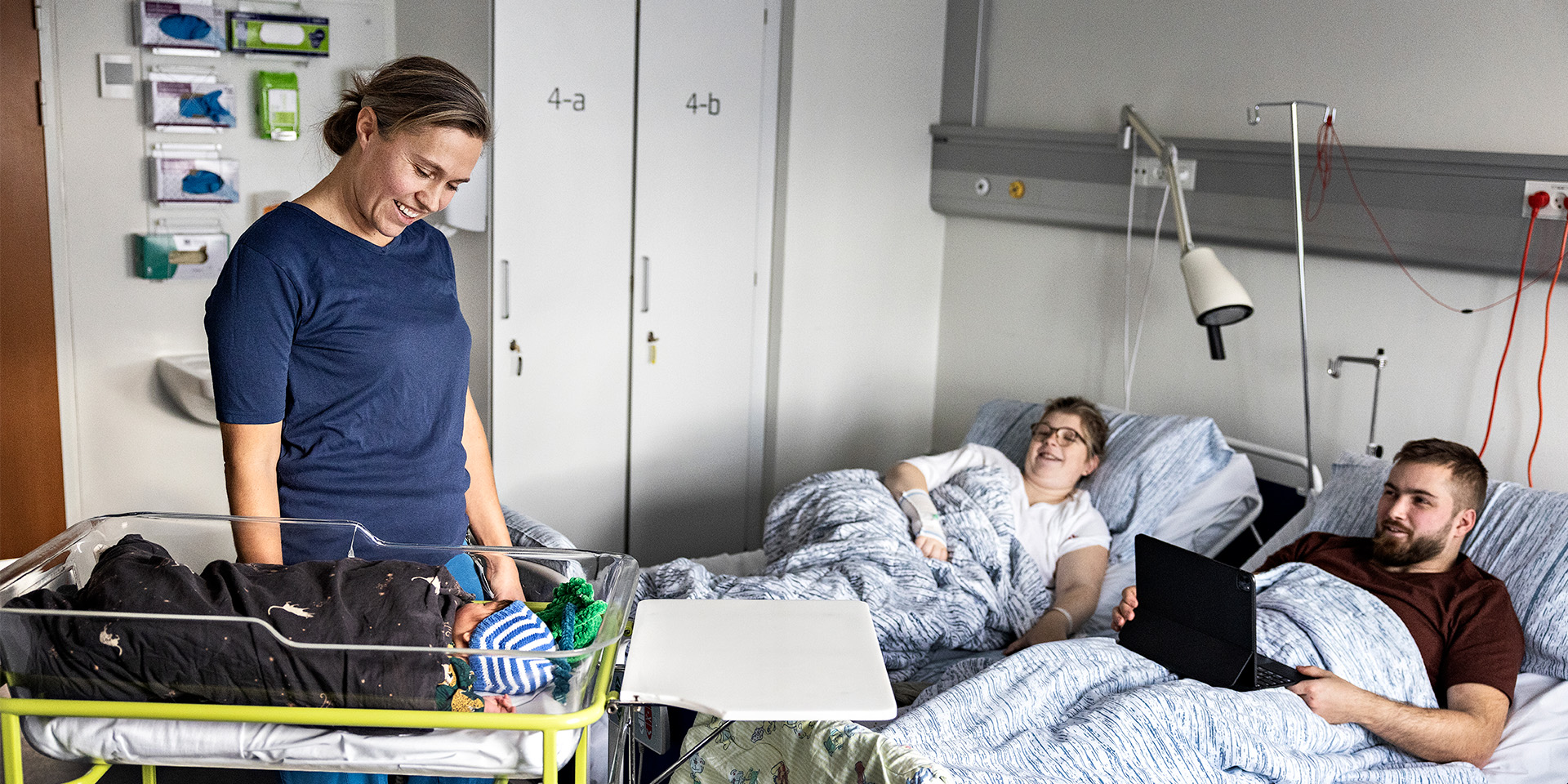 En jordmoder står med en baby og et par nybagte forældre