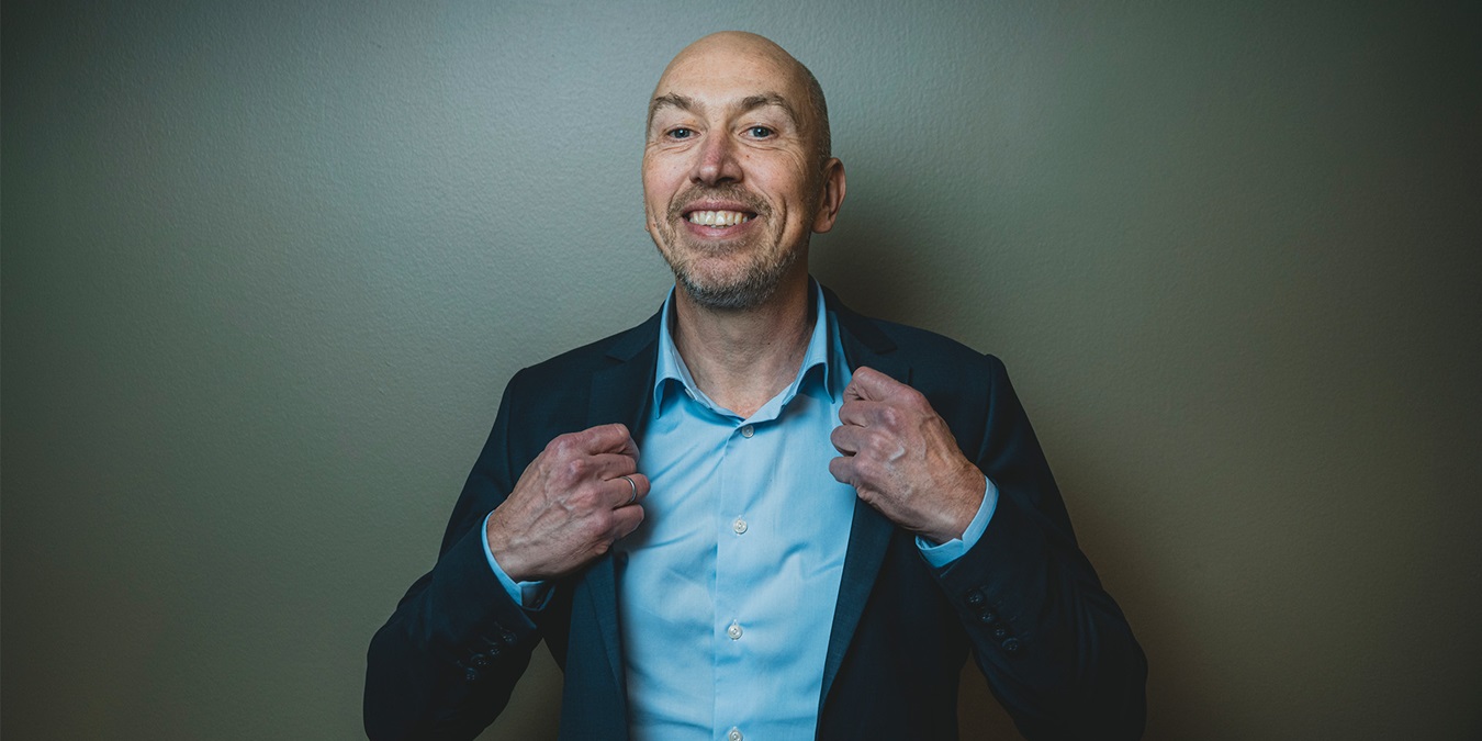 Jakob Keinicke Sørensen smiler til kameraret og holder i kraven på hans skjorte