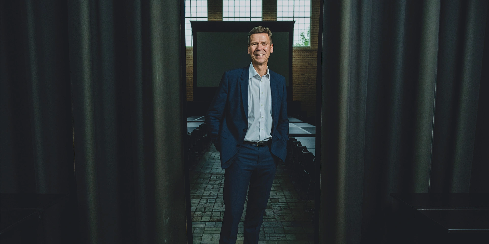 Nomineret til Årets Leder 2022, Jesper Hjulmand står mellem to gardiner og griner