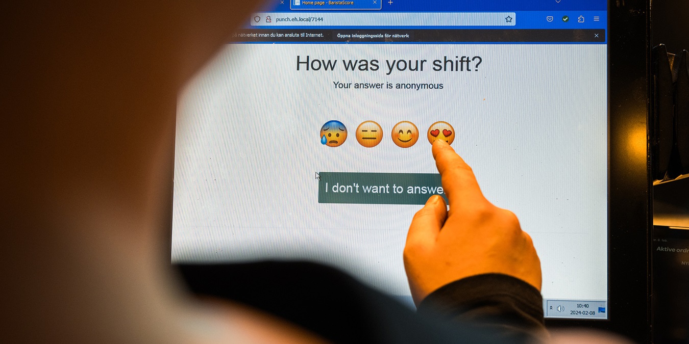 En medarbejder benytter trivselsmålingsskærmen med smileyer