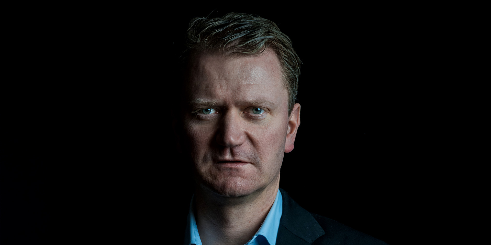 Kasper Fangel står foran en mørk baggrund