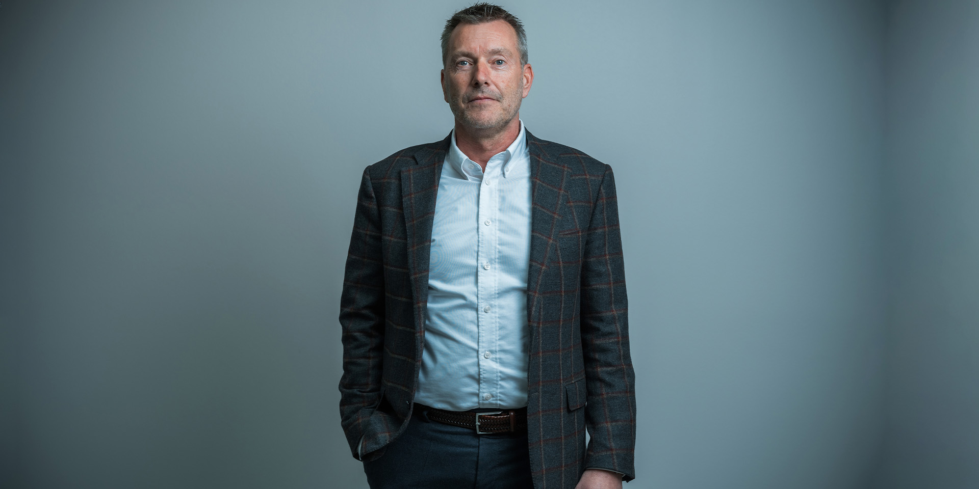 Kim Haldne står foran en grå baggrund med hånden i lommen