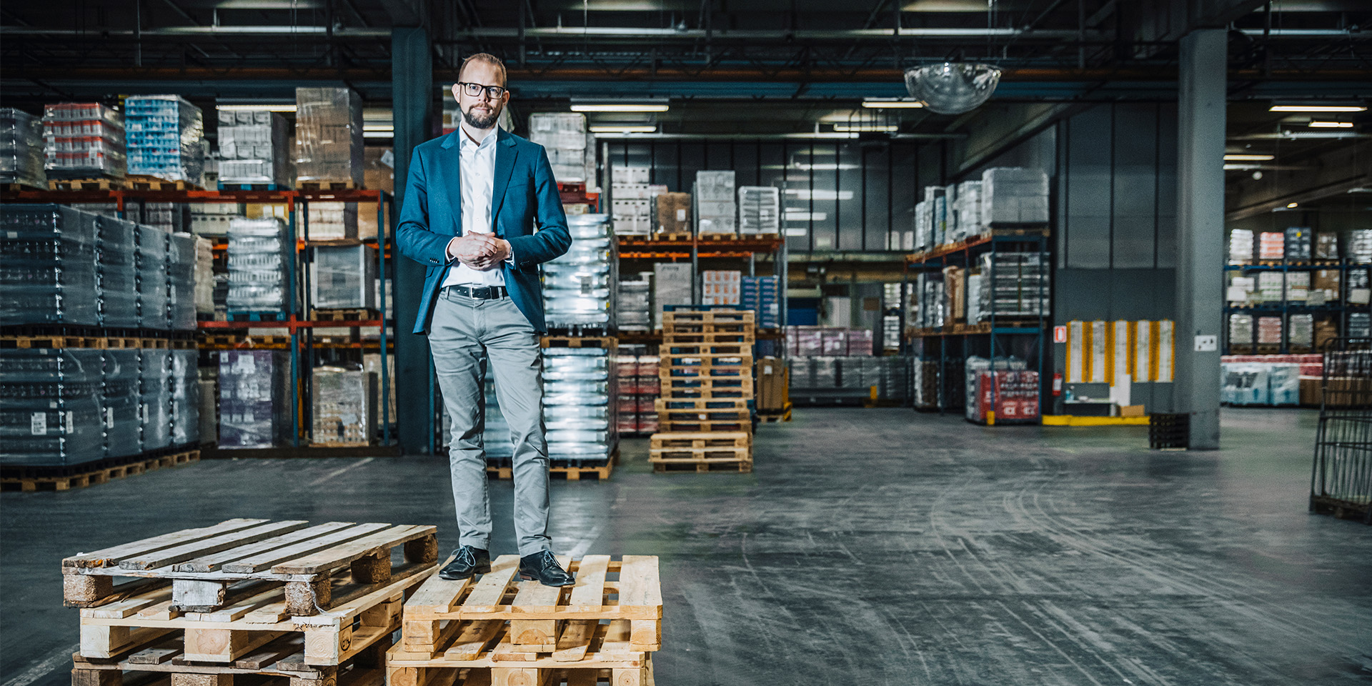 Kræn Østergård står på nogle paler på et lager