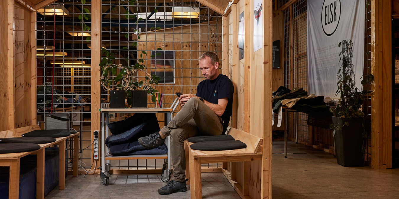 Lars Riis sidder på en bænk på ELSK's kontor med sin telefon