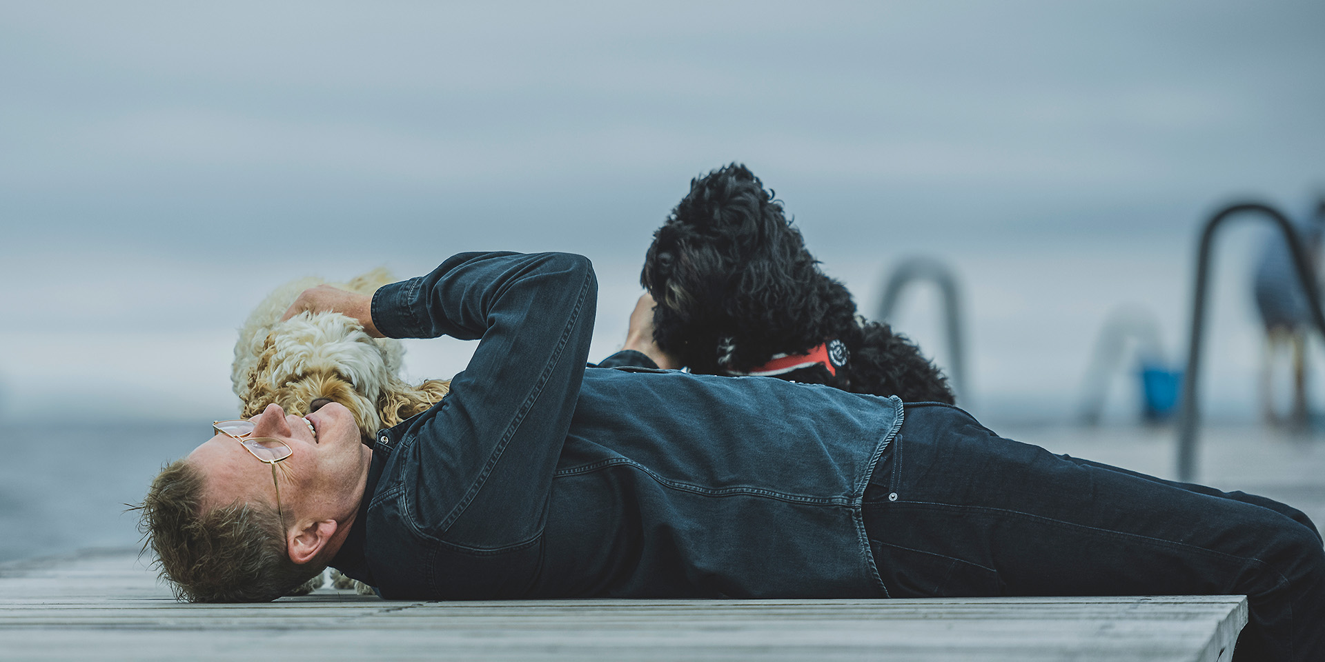 Lars Sander Matjeka ligger på en badebro med sine hunde på Amager Strandpark