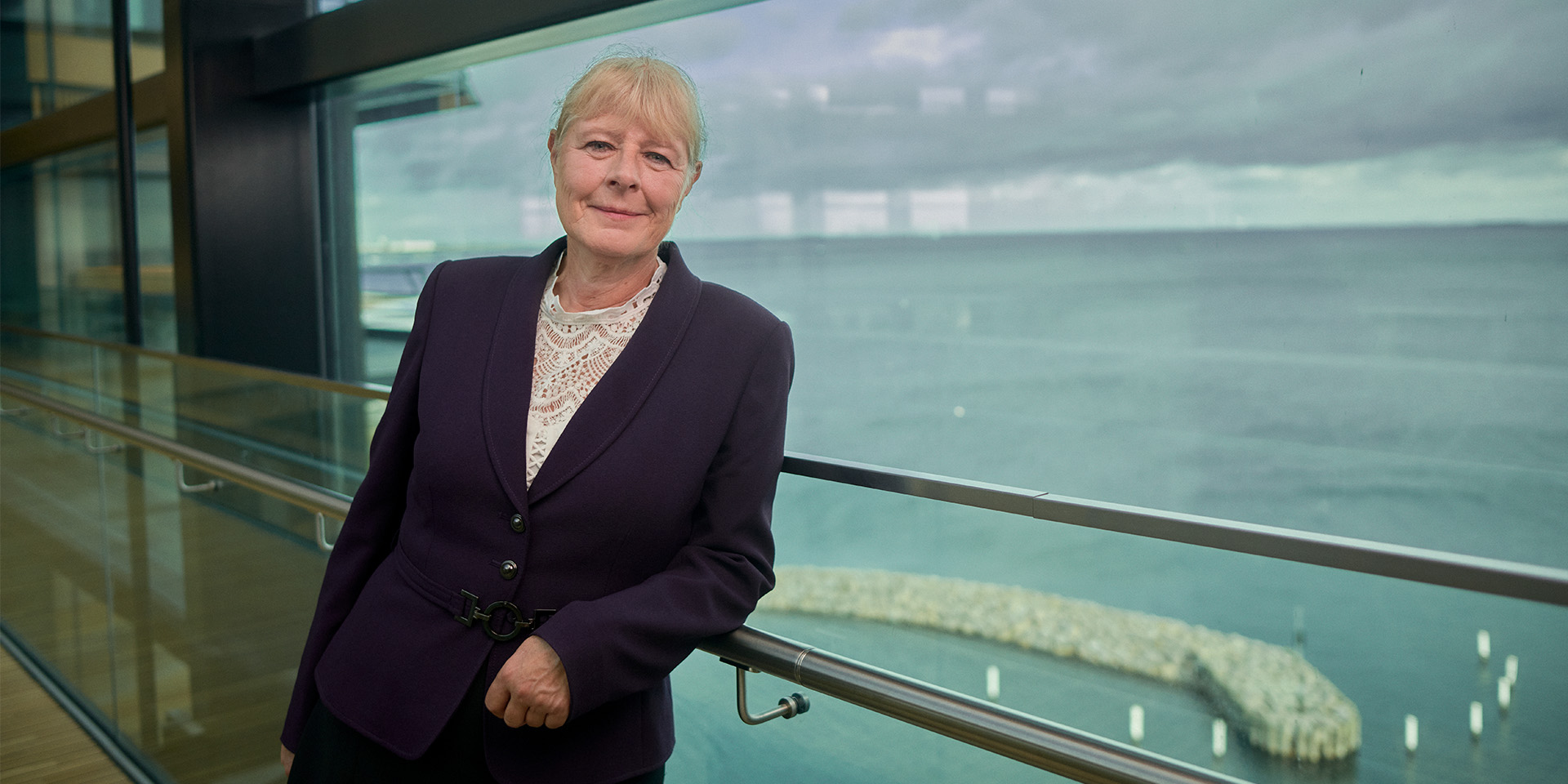 Marianne Kock står ved et rækværk foran en smuk udsigt