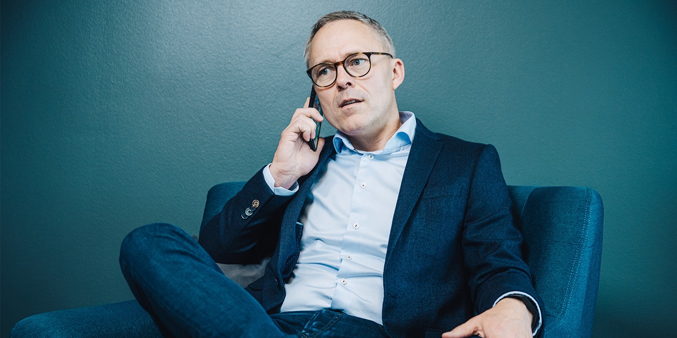 Michael Løve sidder i en lænestol og taler i telefon