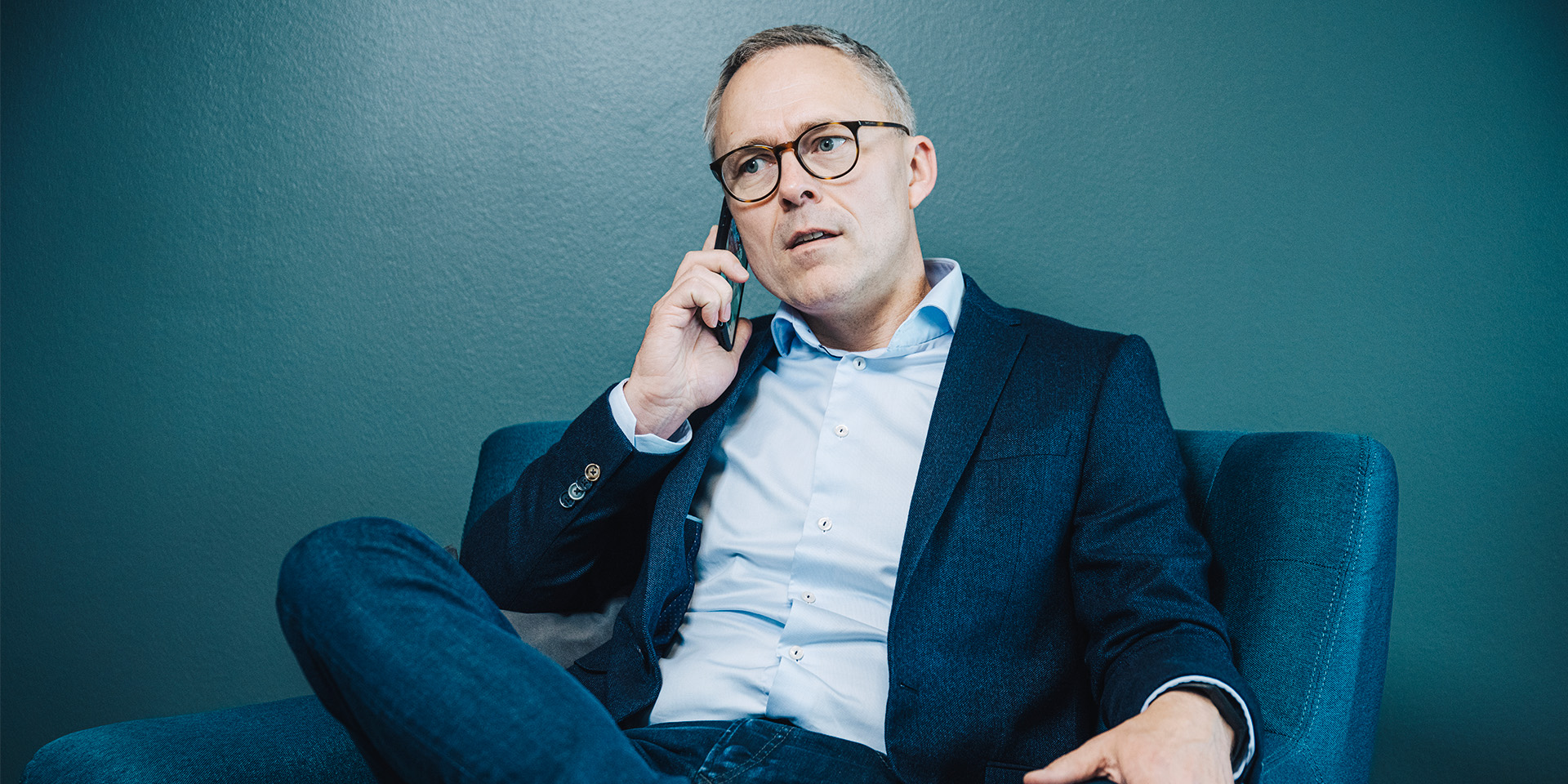 Michael Løve sidder i en lænestol og taler i telefon