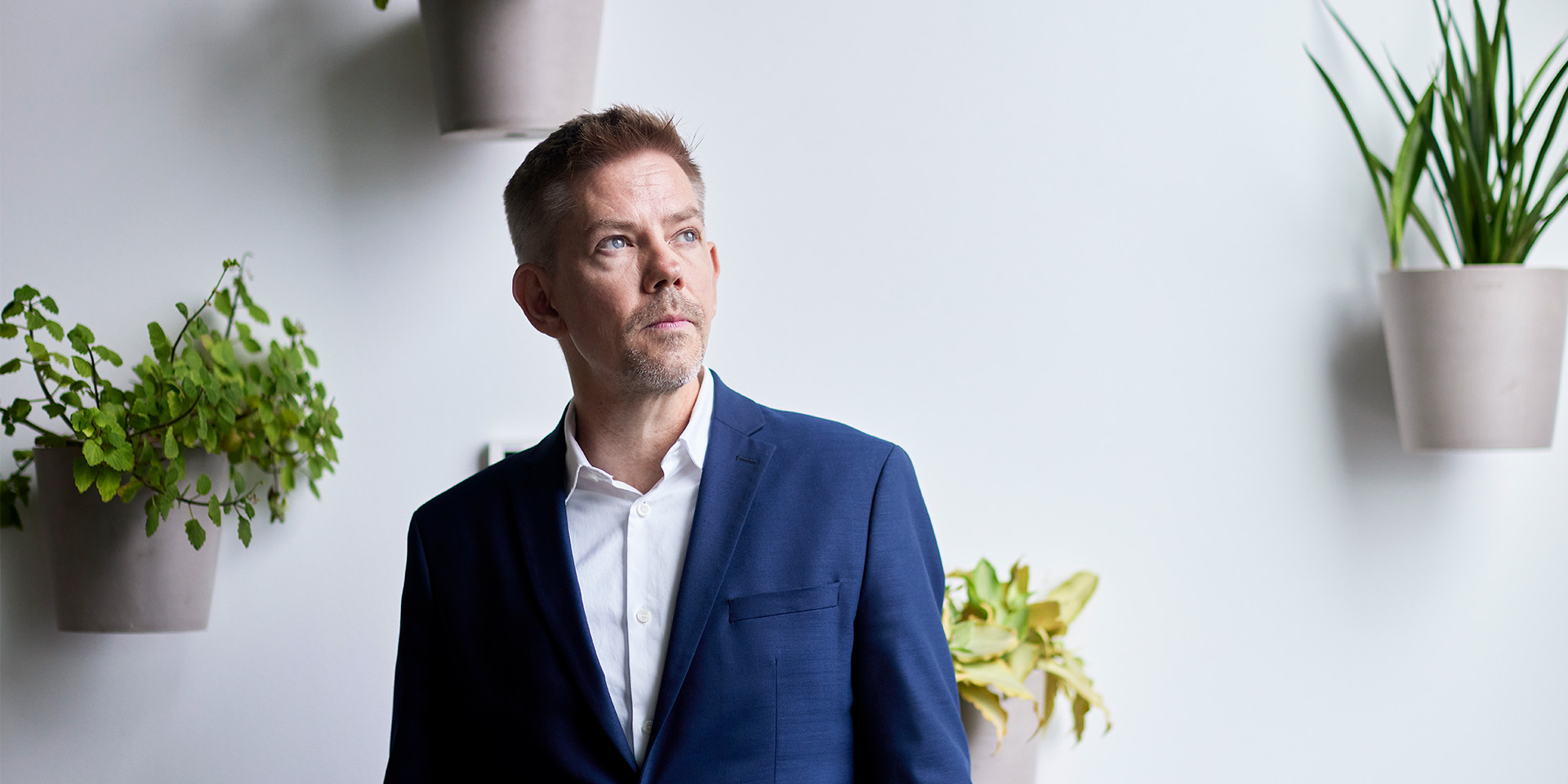 Mikkel Grene står foran en væg med planter på