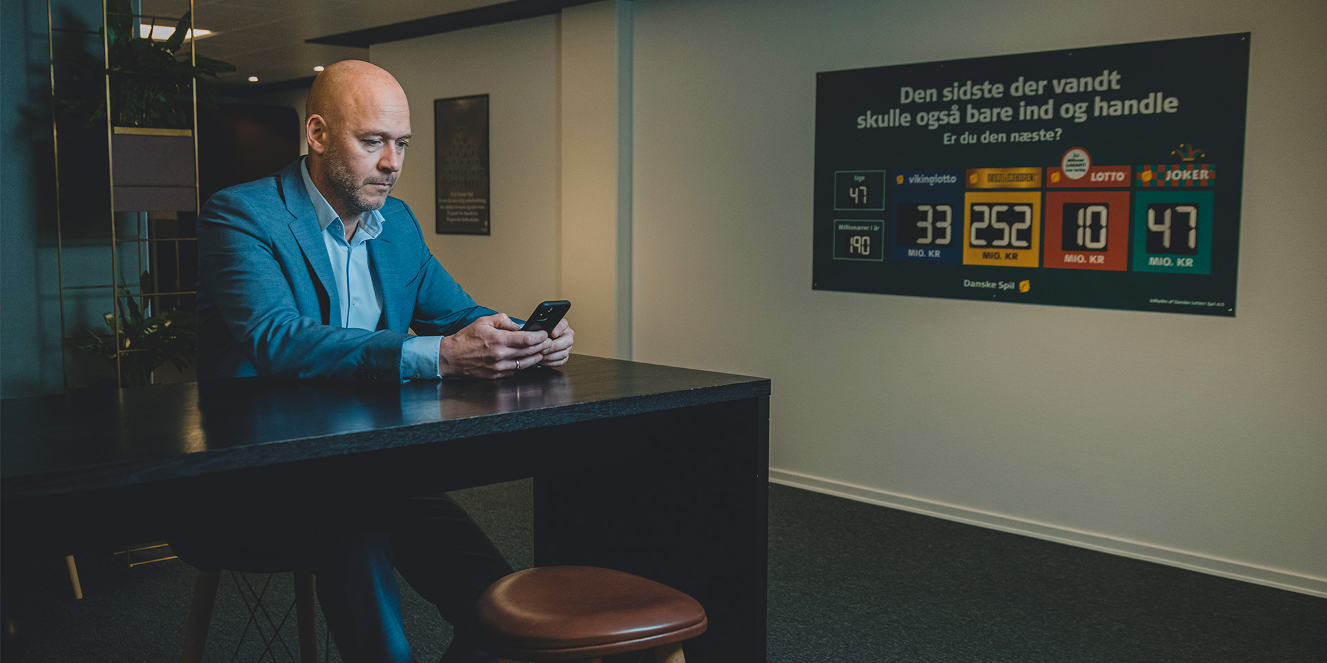 Nikolas Lyhne-Knudsen sidder på Danske Spils kontor og tjekker sin telefon