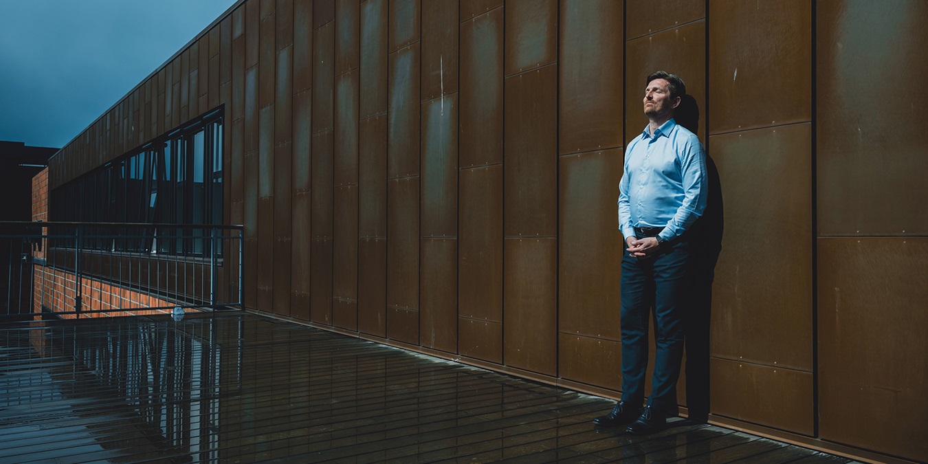 Ole Krogh Petersen står og læner sig op ad en væg udenfor