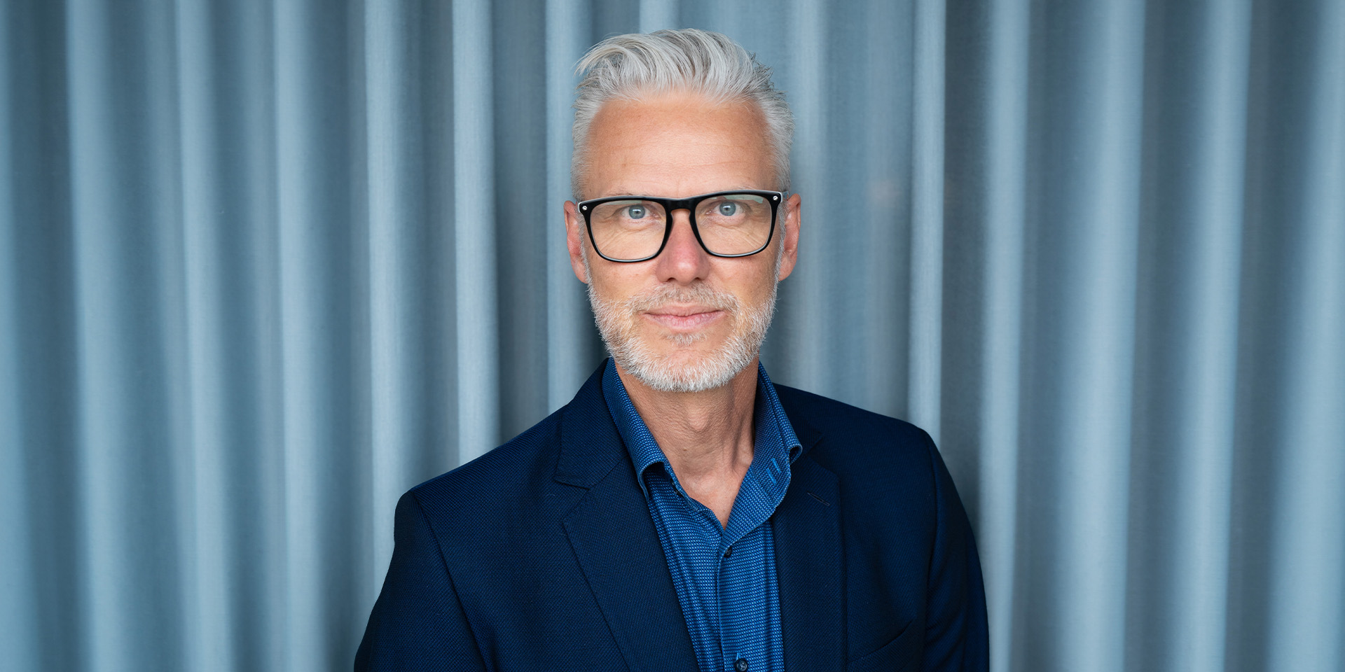 Palle Knudsen står foran en blå baggrund