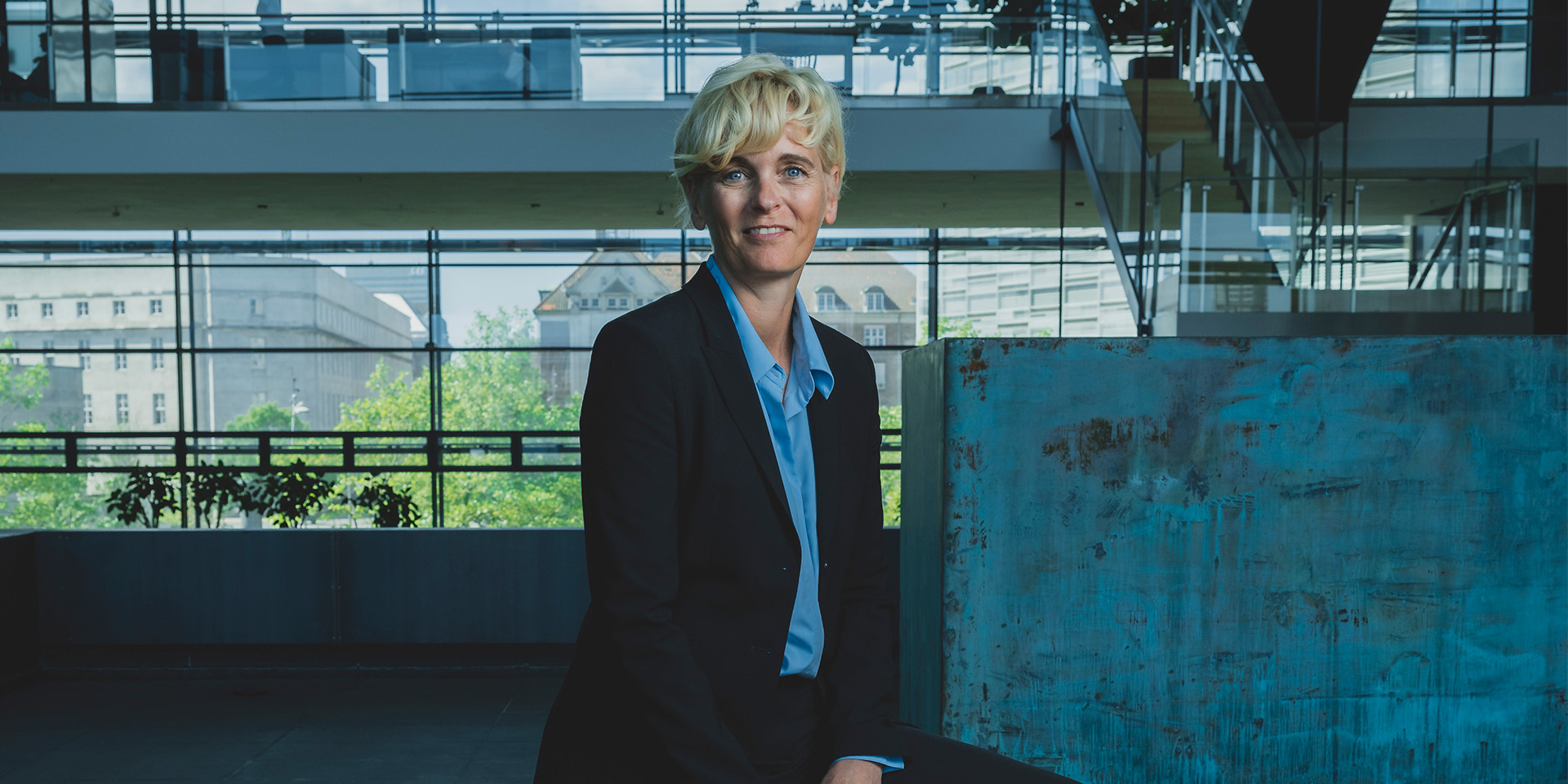 Pernille Sindby sidder på en kant og smiler til kameraret