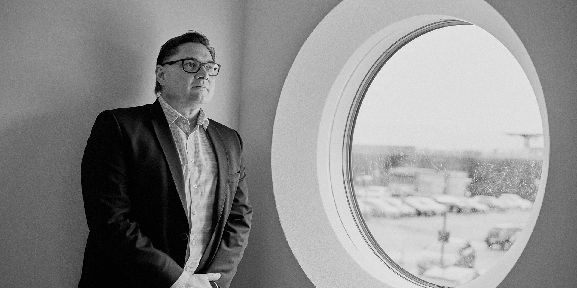 Sort hvid billede af Peter Kjær ved siden af et vindue