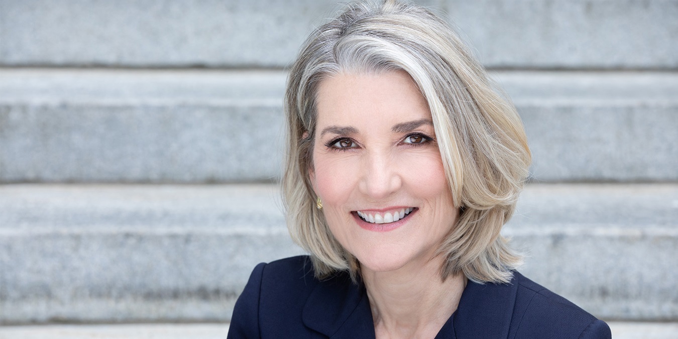 Amy Edmundson smiler og sidder på en trappe