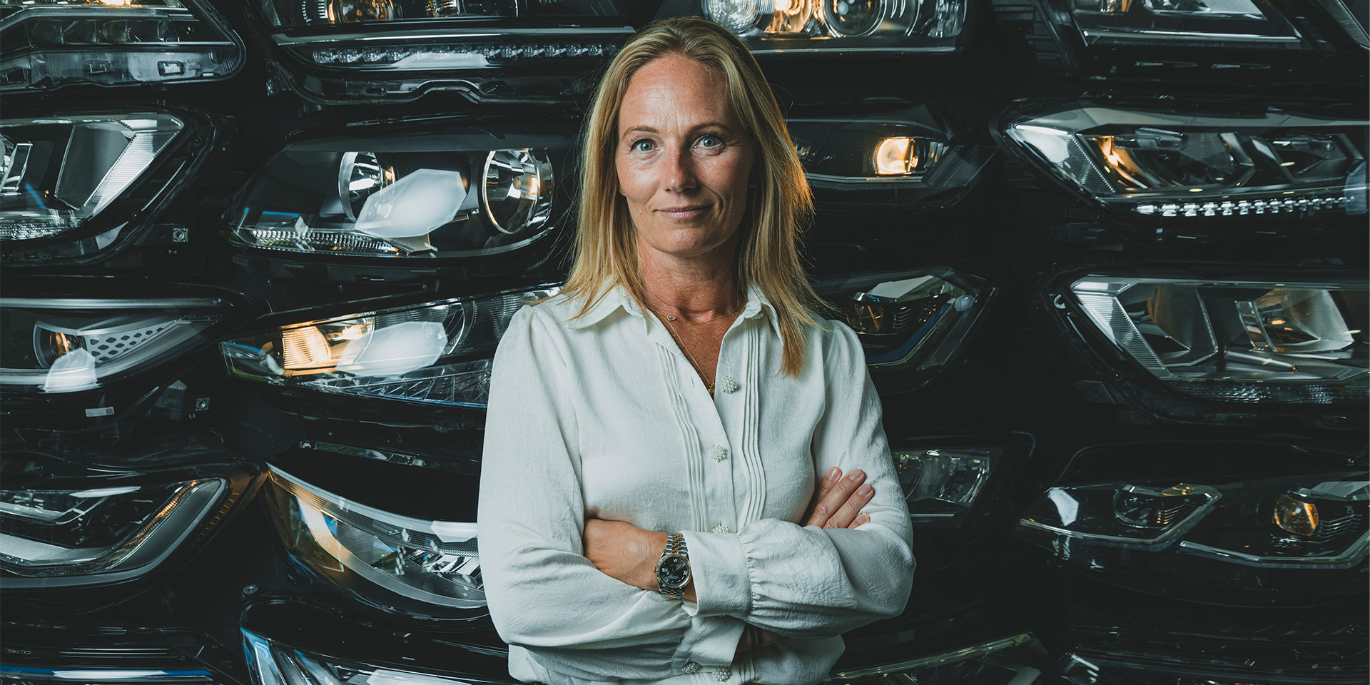 Rikke Hamilton står på sit kontor foran en dekoration af forlygter