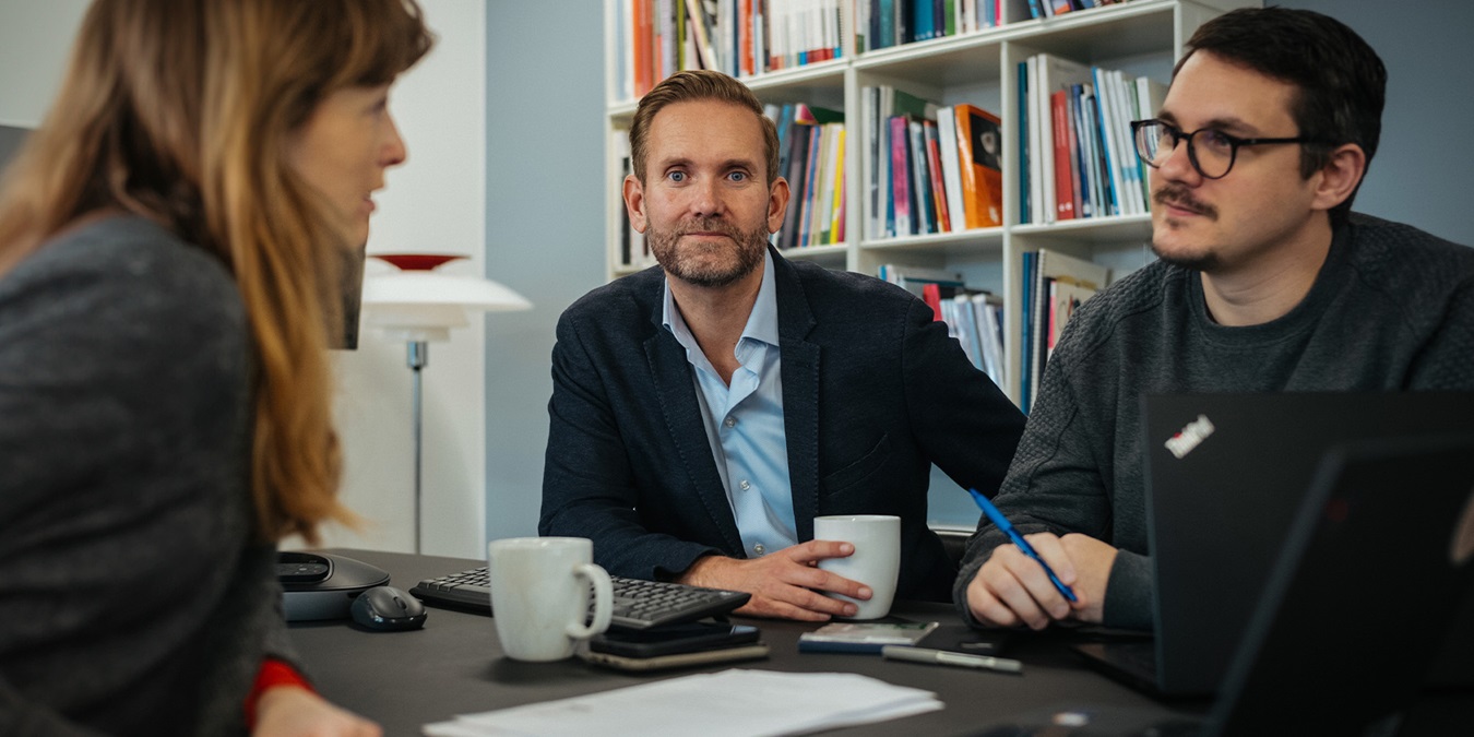 Tommy Zwicky sidder mellem to kollegaer og snakker