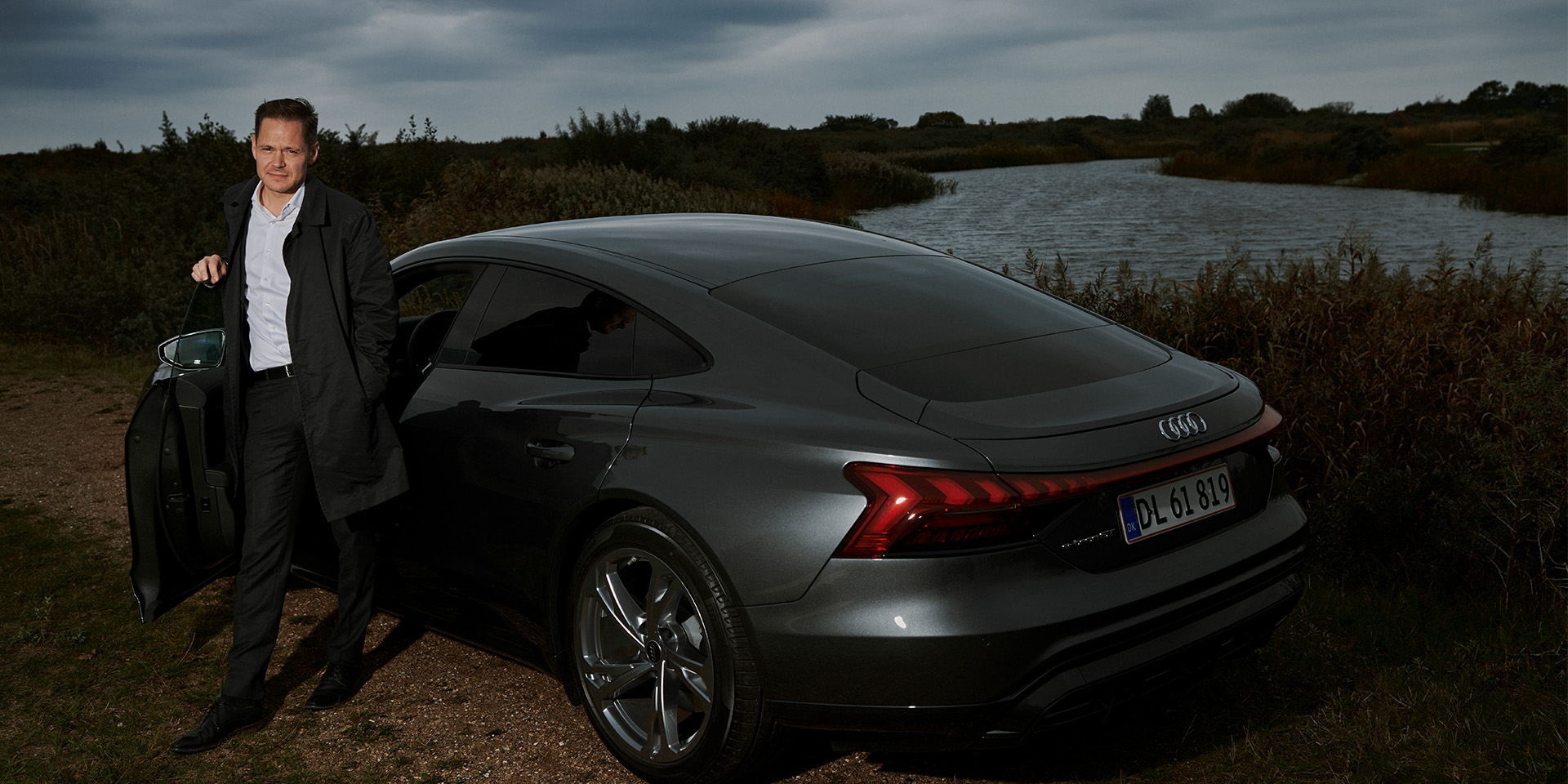 Ulrik Drejsig står ved en sø og læner sig op ad en Audi
