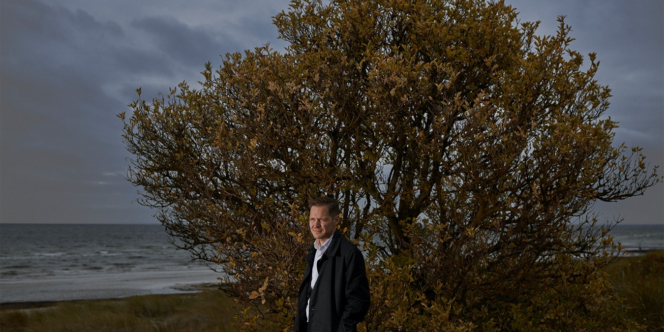 Ulrik Drejsig står på en strand foran et træ